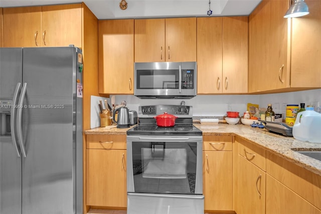 kitchen with appliances with stainless steel finishes and light stone countertops