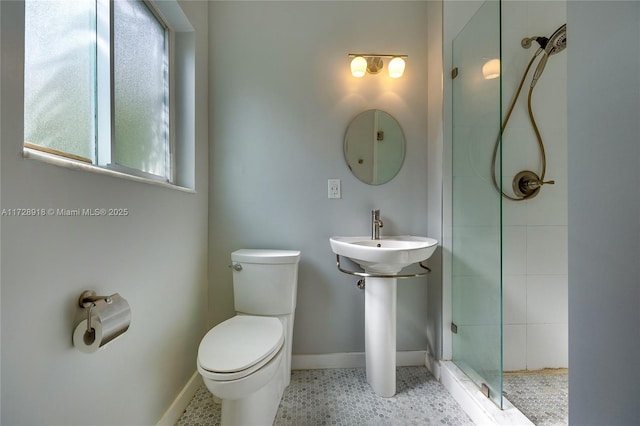 bathroom with sink, a tile shower, and toilet