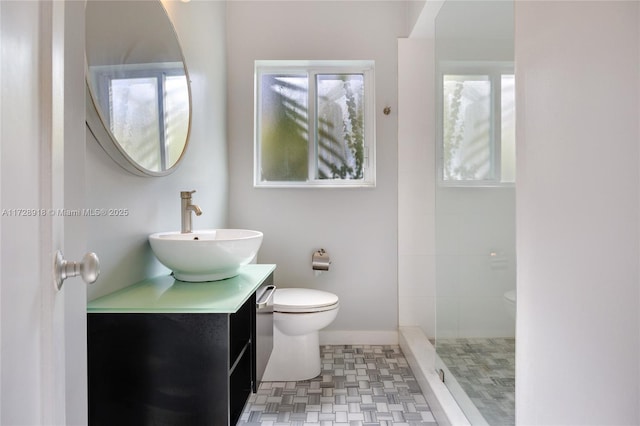 bathroom featuring vanity, a healthy amount of sunlight, tiled shower, and toilet