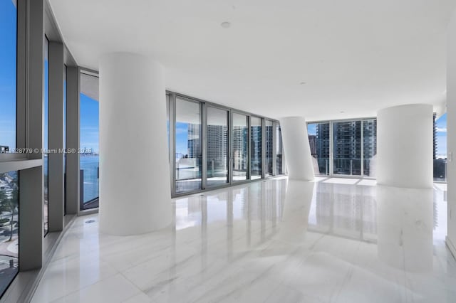 unfurnished room with floor to ceiling windows and a water view