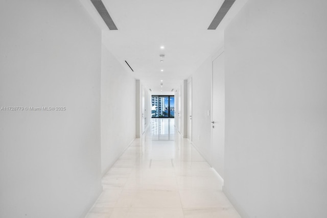 hallway featuring baseboards, a wall of windows, visible vents, and recessed lighting