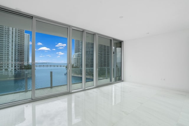 unfurnished room with a water view and a wall of windows