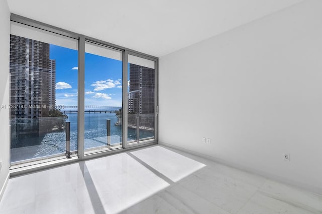 tiled spare room with a water view and a wall of windows