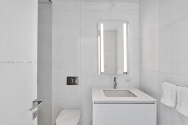 bathroom with tile walls, toilet, and vanity