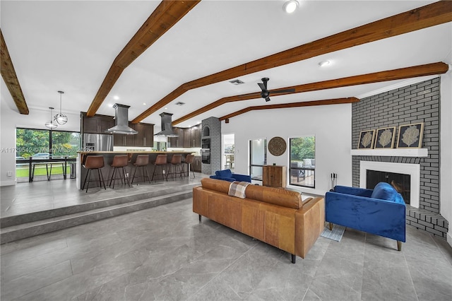 living room featuring vaulted ceiling with beams, a wealth of natural light, and a brick fireplace