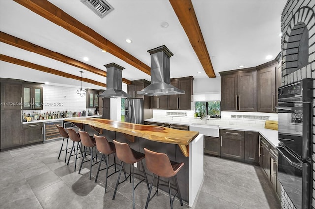 kitchen with sink, backsplash, island range hood, and beam ceiling