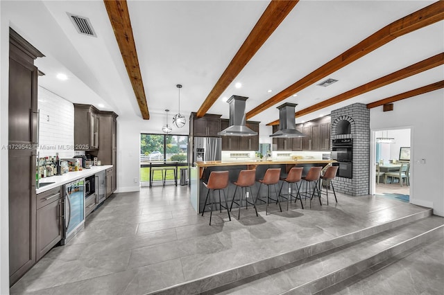 kitchen featuring decorative light fixtures, beamed ceiling, island range hood, and stainless steel fridge with ice dispenser