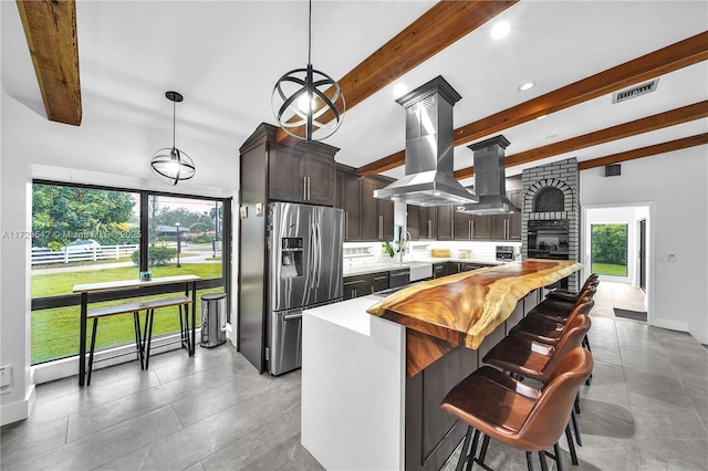 kitchen with a center island, hanging light fixtures, island exhaust hood, dark brown cabinets, and stainless steel fridge