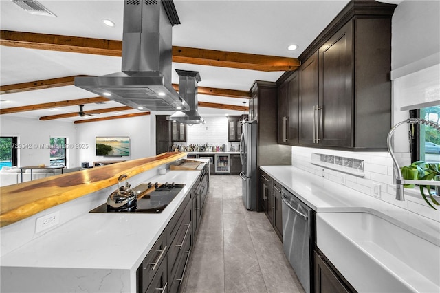 kitchen with stainless steel appliances, sink, backsplash, island range hood, and lofted ceiling with beams