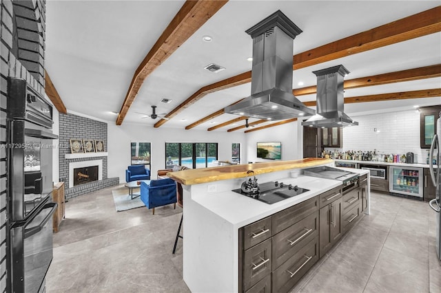 kitchen featuring a center island, black appliances, island range hood, and lofted ceiling with beams