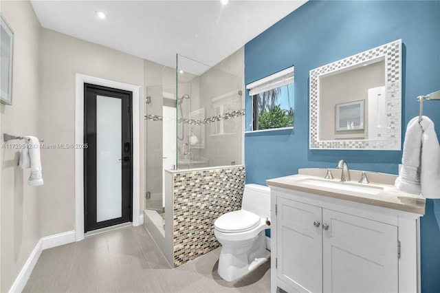 bathroom featuring toilet, tiled shower, and vanity