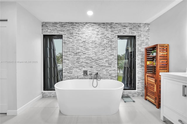 bathroom with a tub to relax in, tile patterned flooring, and vanity