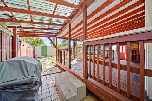 wooden terrace featuring an outdoor structure, grilling area, and a storage shed