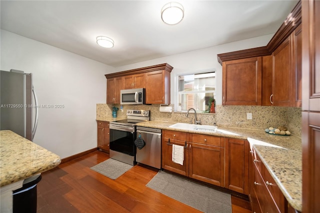 kitchen featuring a sink, appliances with stainless steel finishes, backsplash, brown cabinets, and dark wood-style floors