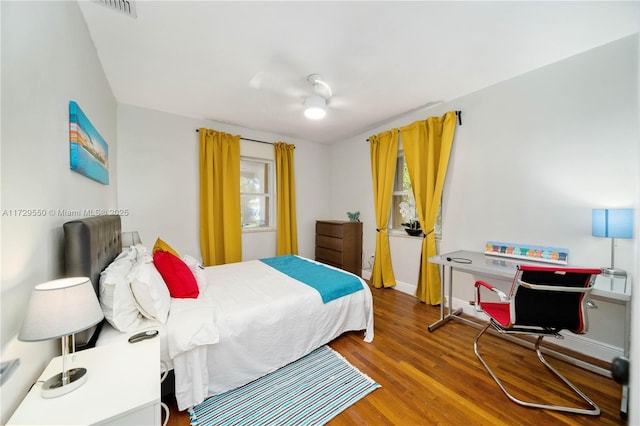 bedroom with a ceiling fan, wood finished floors, visible vents, and baseboards