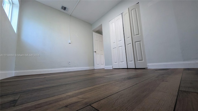 spare room with dark wood-style floors, lofted ceiling, visible vents, and baseboards