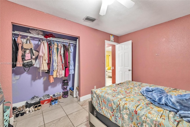 tiled bedroom with ceiling fan and a closet