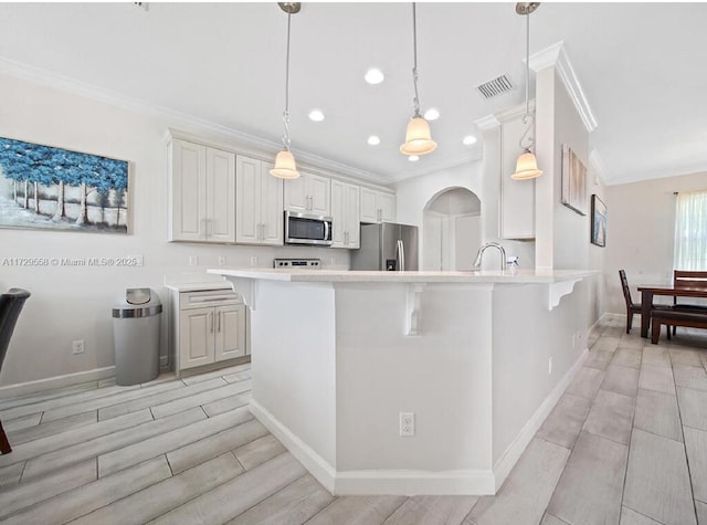 kitchen featuring decorative light fixtures, stainless steel appliances, and ornamental molding