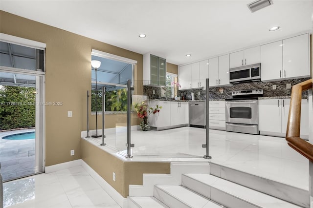 kitchen with white cabinetry, stainless steel appliances, sink, and decorative backsplash