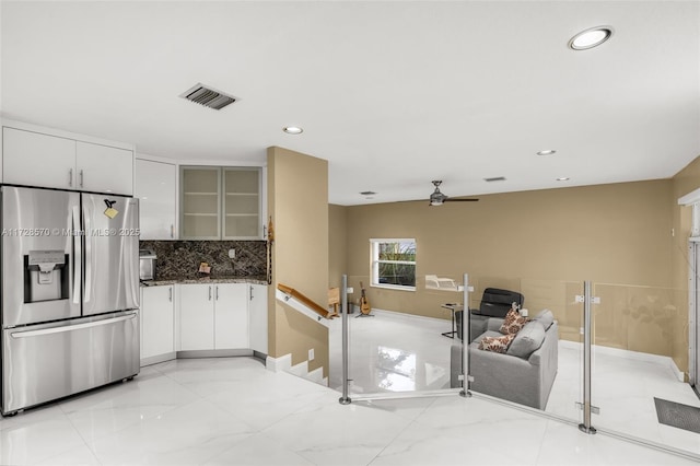 kitchen with stainless steel fridge with ice dispenser, backsplash, and white cabinets