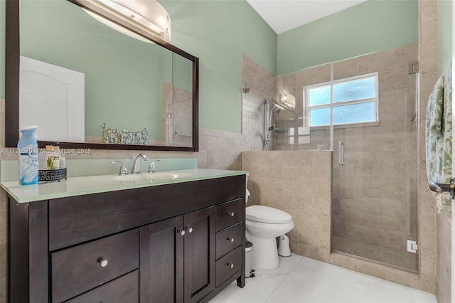 bathroom featuring tile patterned flooring, tile walls, vanity, a shower with shower door, and toilet