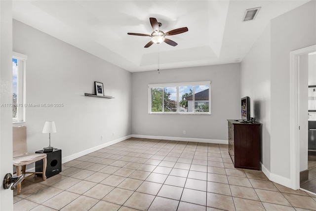 unfurnished living room featuring light tile patterned floors, a tray ceiling, and ceiling fan