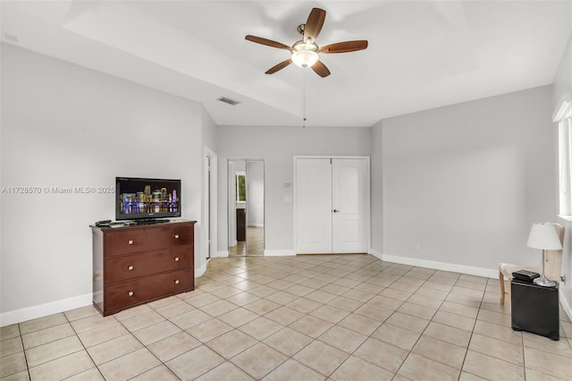 living room featuring light tile patterned flooring, ceiling fan, and a tray ceiling