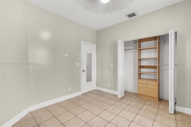 unfurnished bedroom with light tile patterned floors, ceiling fan, and a closet