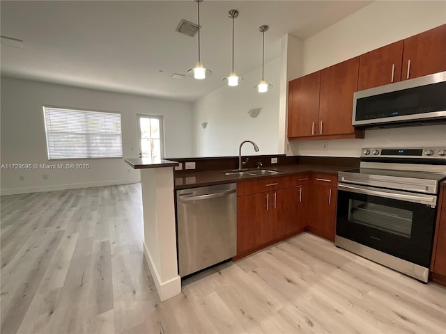 kitchen featuring decorative light fixtures, stainless steel appliances, sink, kitchen peninsula, and light hardwood / wood-style flooring