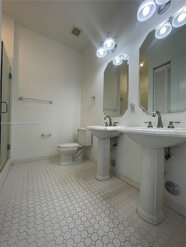 bathroom with toilet, tile patterned flooring, sink, and a shower with shower door