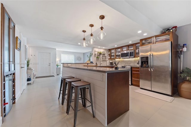 kitchen featuring decorative light fixtures, a center island, stainless steel appliances, beverage cooler, and backsplash