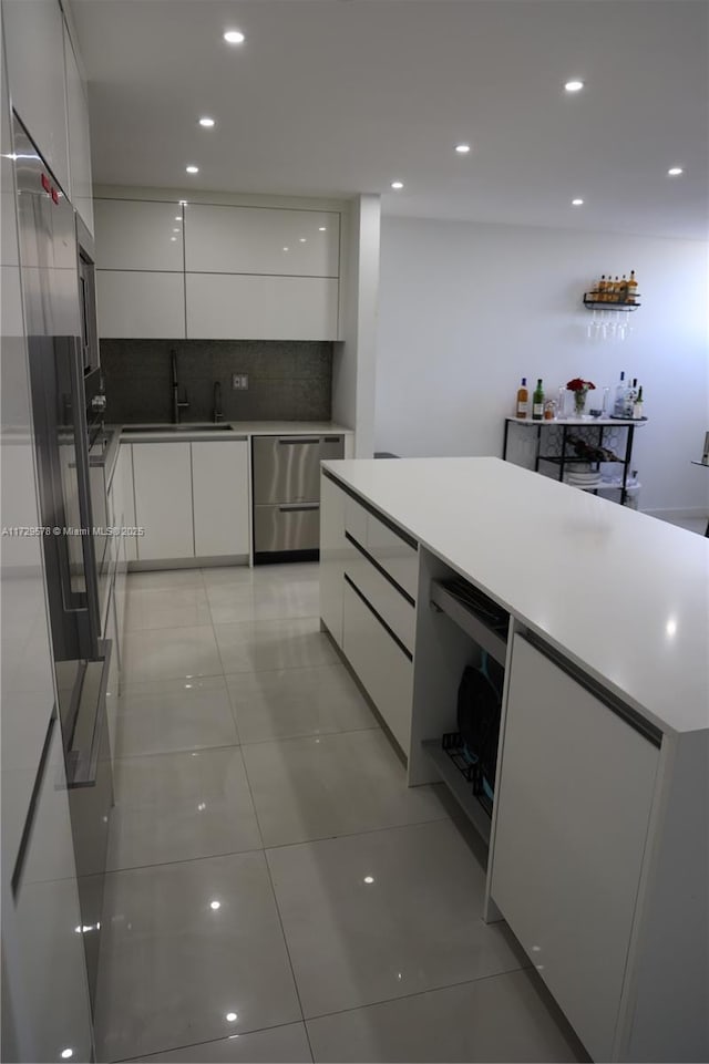 kitchen with white cabinetry, stainless steel dishwasher, light tile patterned floors, and decorative backsplash