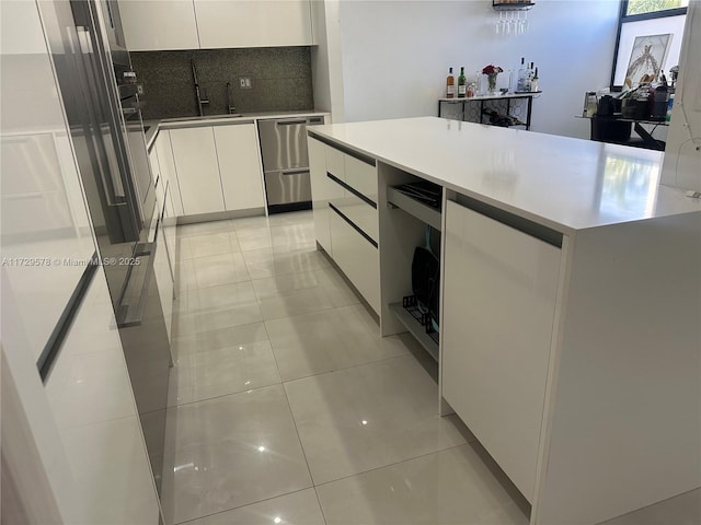 kitchen with white cabinetry, a center island, light tile patterned flooring, decorative backsplash, and stainless steel dishwasher