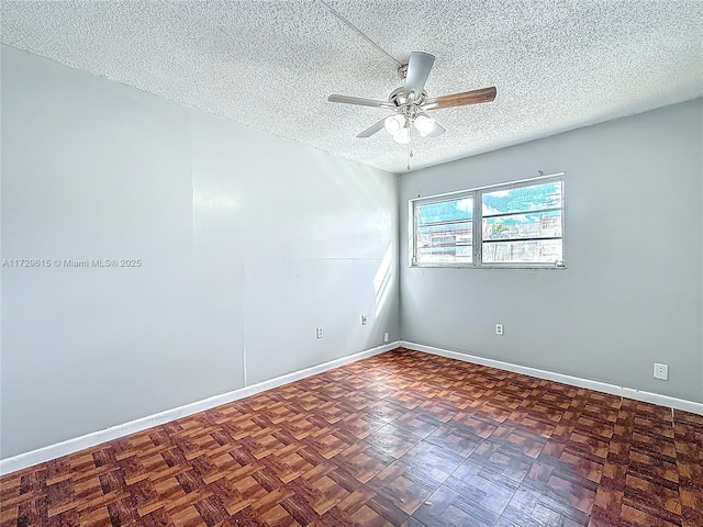 empty room with a textured ceiling, ceiling fan, and baseboards