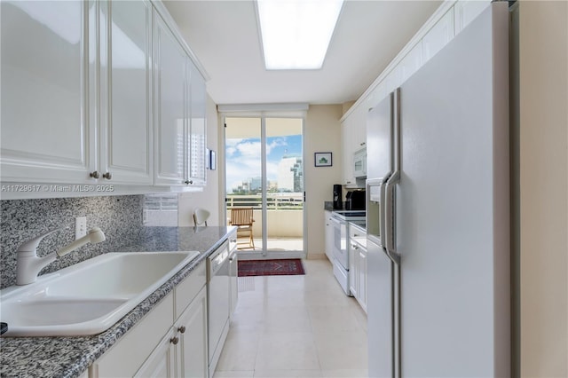 kitchen featuring decorative backsplash, sink, white appliances, expansive windows, and white cabinets