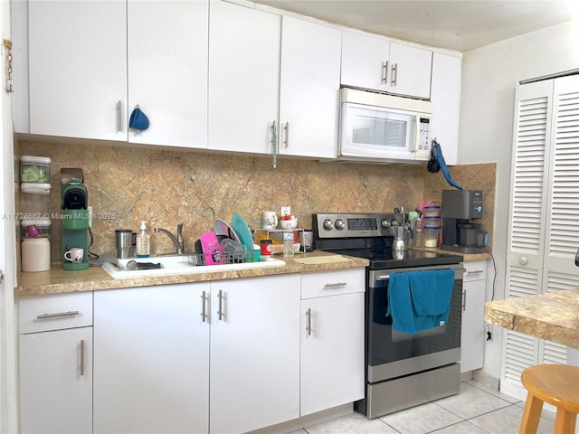 kitchen featuring backsplash, sink, light tile patterned flooring, white cabinetry, and stainless steel range with electric cooktop