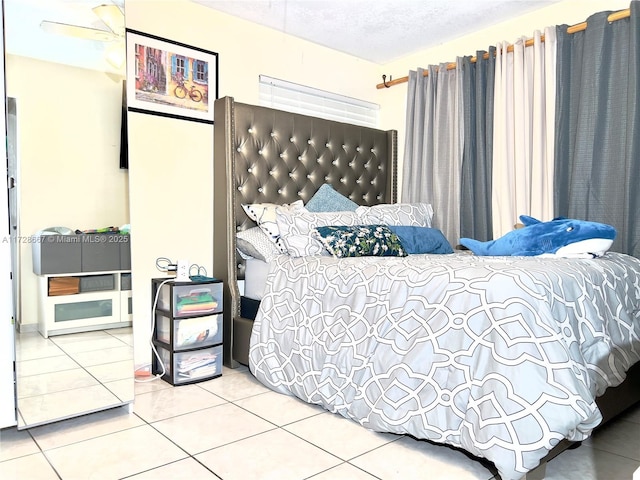 tiled bedroom with ceiling fan and a textured ceiling