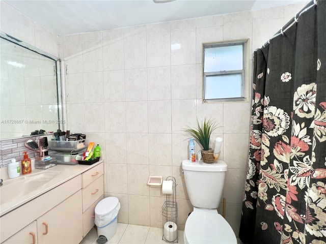 bathroom with toilet, vanity, tile walls, and walk in shower