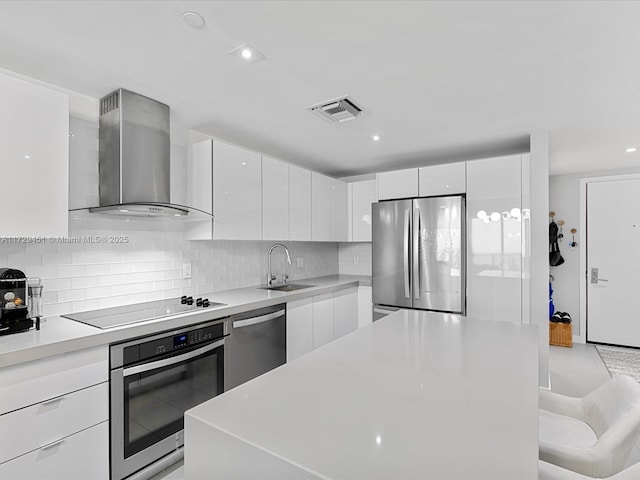 kitchen with sink, tasteful backsplash, white cabinetry, wall chimney range hood, and stainless steel appliances