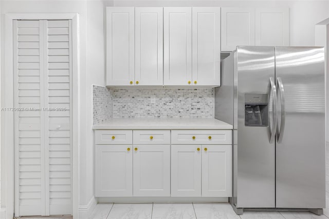 kitchen featuring stainless steel refrigerator with ice dispenser, decorative backsplash, and white cabinetry