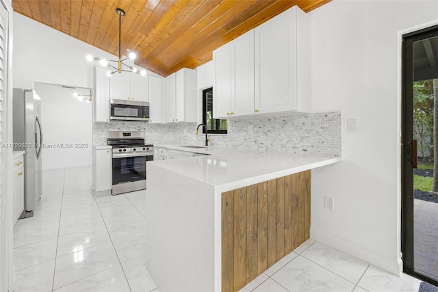 kitchen with lofted ceiling, kitchen peninsula, white cabinetry, hanging light fixtures, and appliances with stainless steel finishes