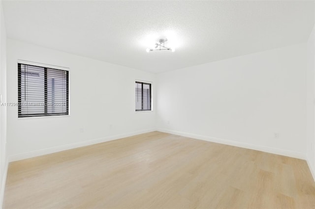 unfurnished room featuring a textured ceiling and light hardwood / wood-style flooring