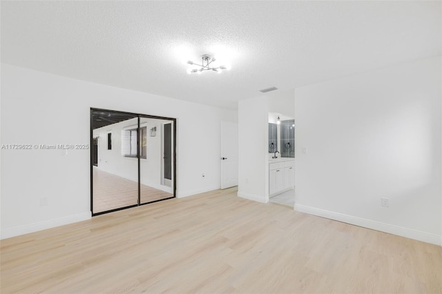 empty room featuring a textured ceiling and light hardwood / wood-style floors