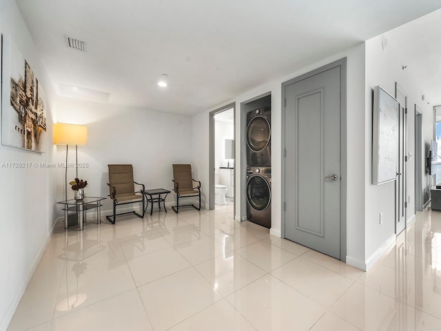 living area featuring light tile patterned floors and stacked washer and clothes dryer