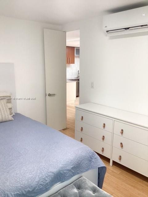 bedroom featuring light hardwood / wood-style floors and a wall mounted air conditioner