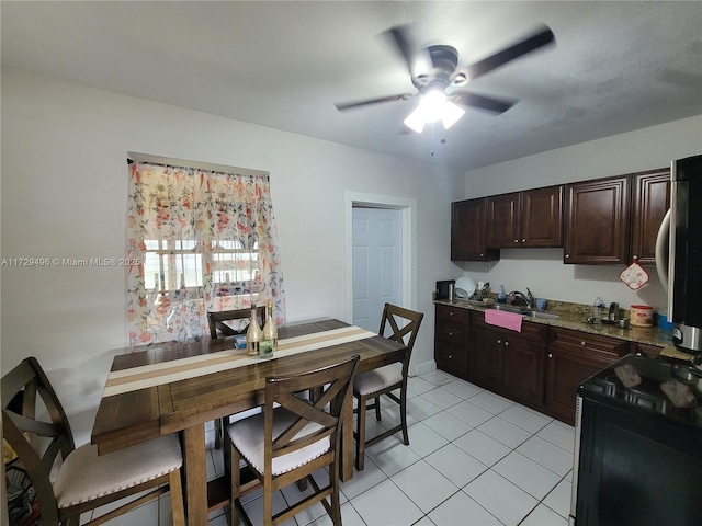 kitchen featuring sink, ceiling fan, electric range, light tile patterned floors, and dark brown cabinets