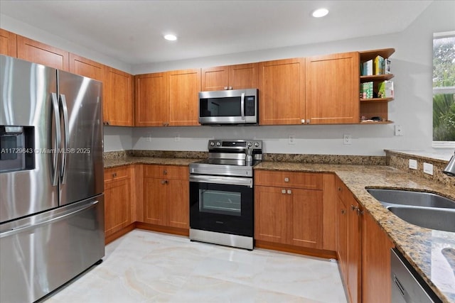 kitchen featuring stainless steel appliances, light stone counters, and sink