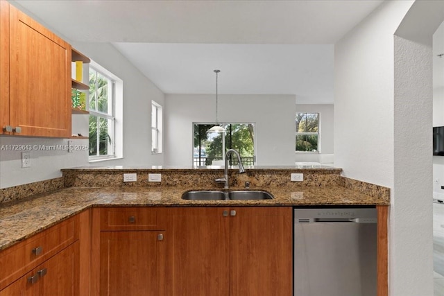 kitchen featuring decorative light fixtures, dishwasher, sink, and dark stone counters