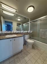 full bathroom featuring toilet, tile patterned floors, vanity, and shower / bath combination with glass door