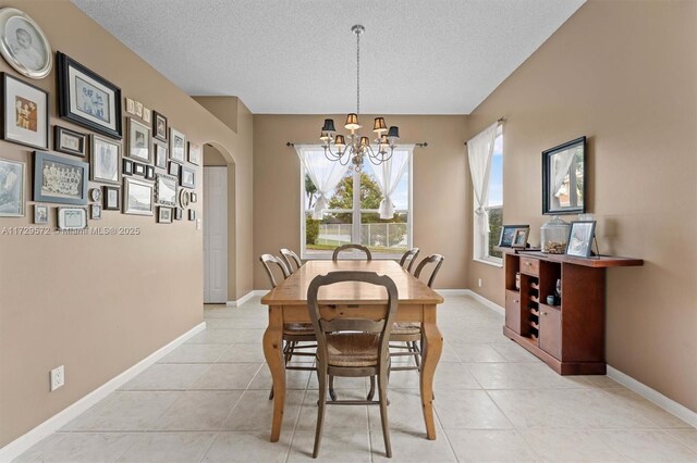 dining room featuring a textured ceiling, light tile patterned floors, and a notable chandelier